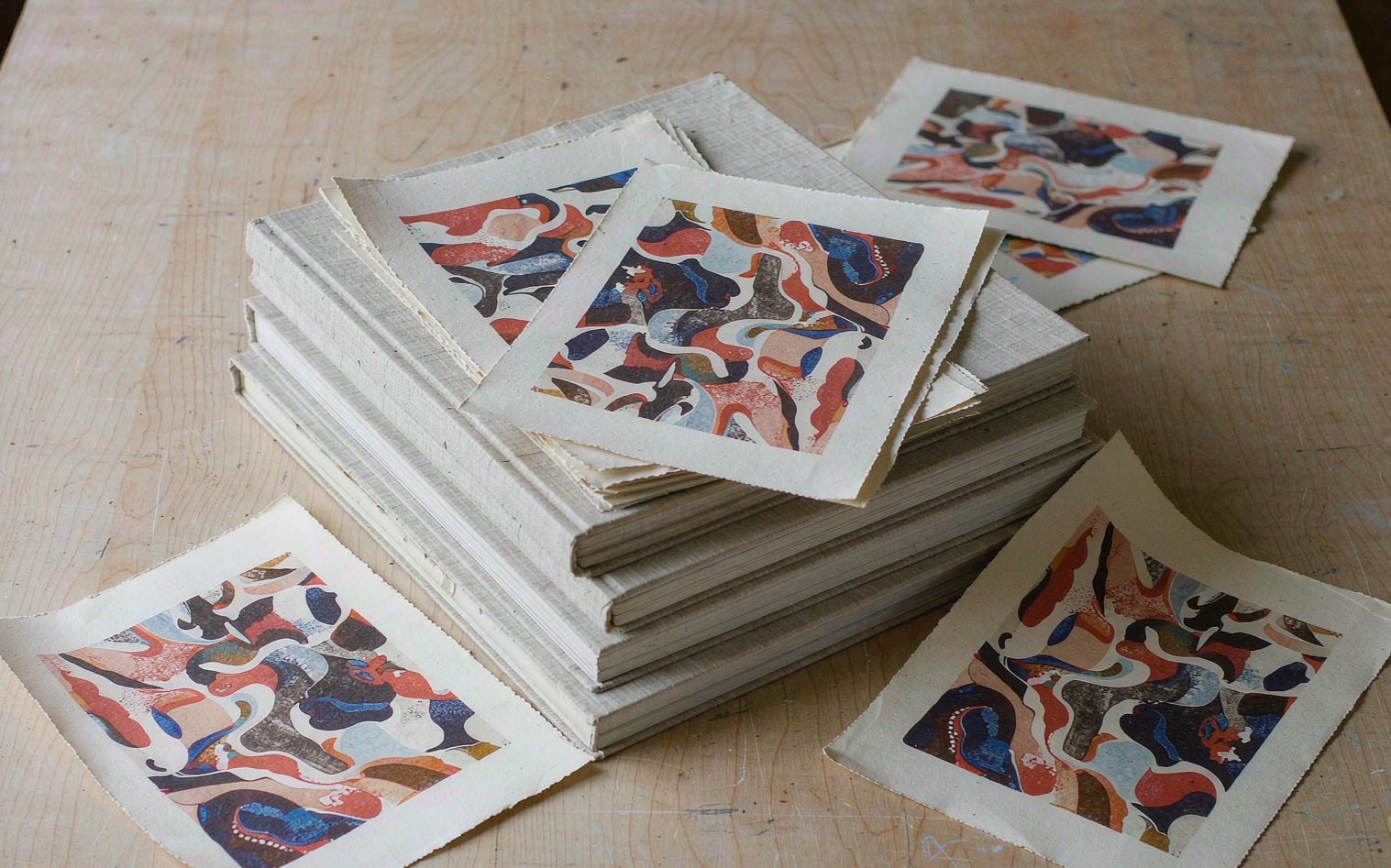 PRESS — art books and risograph prints stacked on an oak table